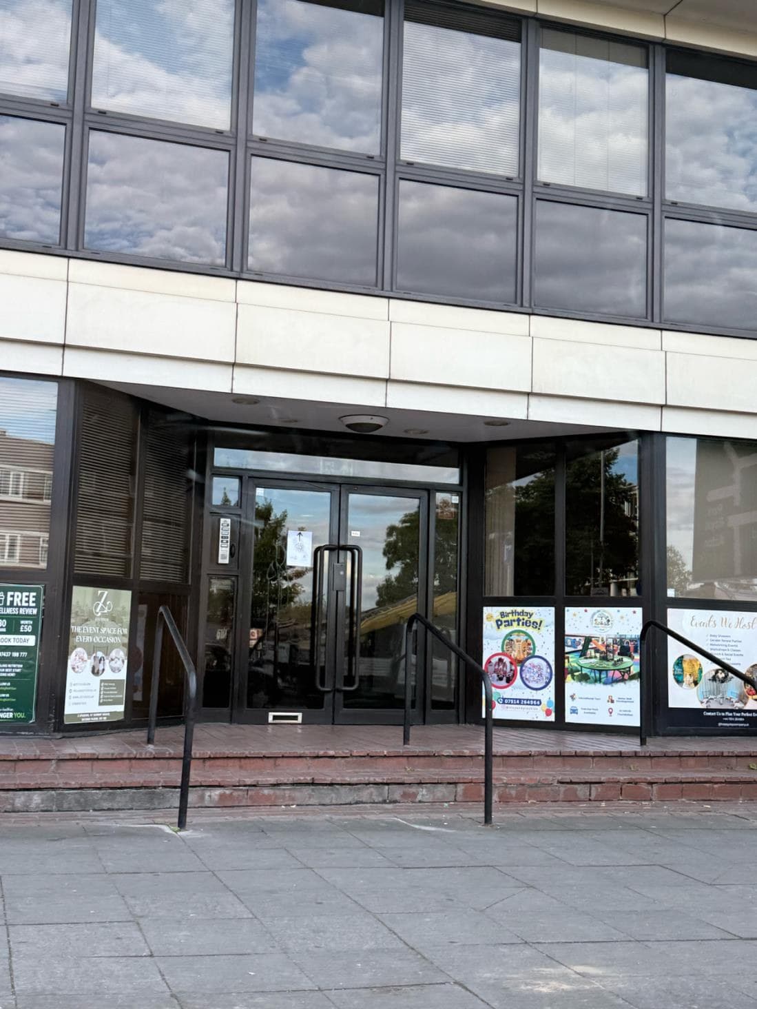 The glass entrance doors of K T Summit House at 100 Hanger Lane, with steps and handrails in front